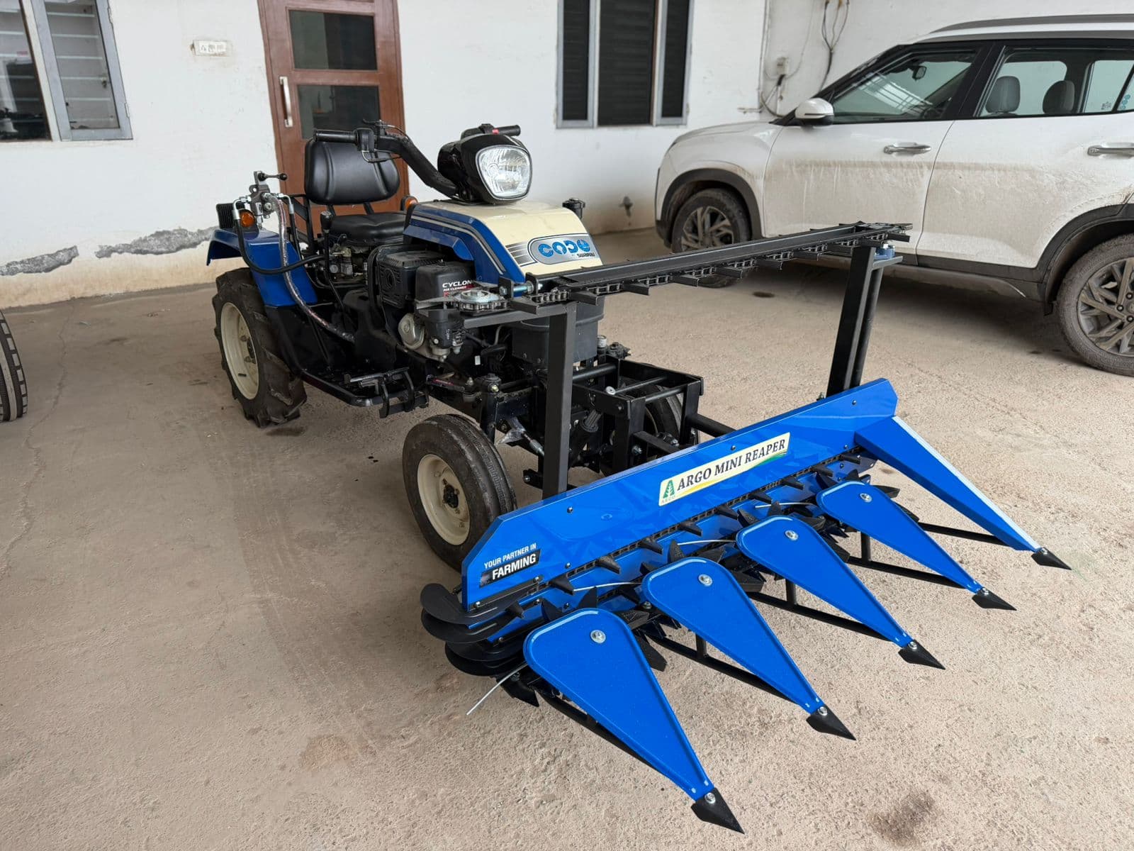 Blue tractor-mounted reaper, side view